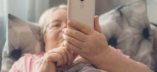 An elderly woman reclining and looking at her phone.