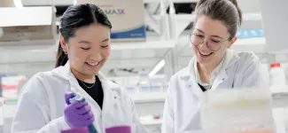Two researchers in a lab; one is holding a pipette.