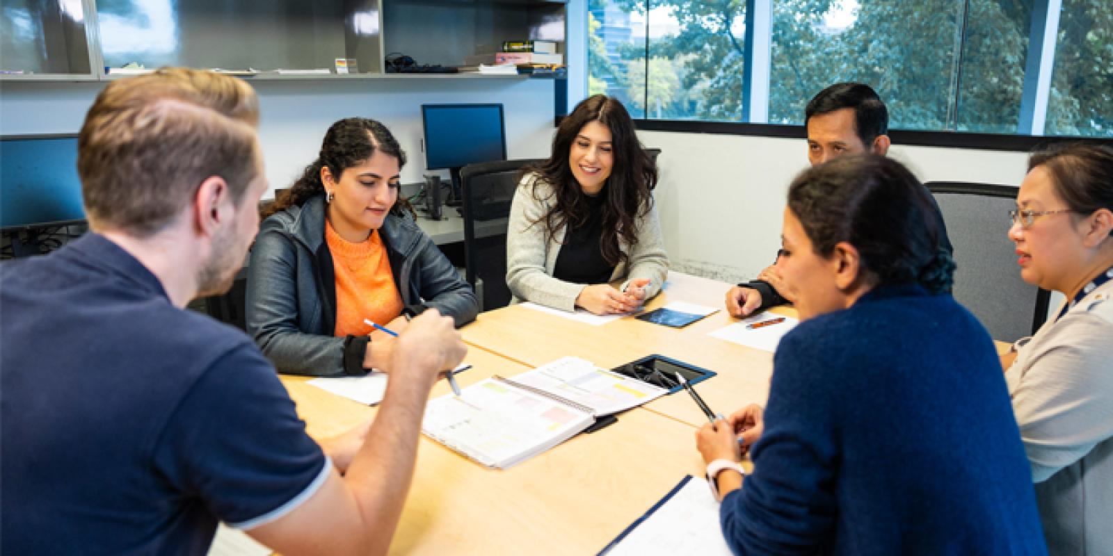 A group of people smiling and conversing in a meeting room.