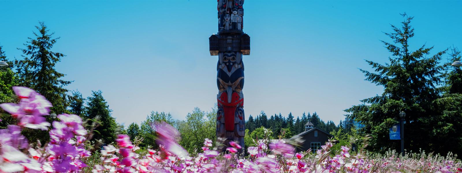 The UBC Reconciliation Pole, with flowers in the foreground.