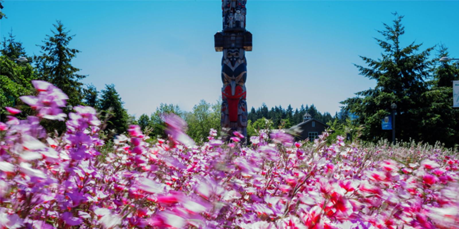 The UBC Reconciliation Pole, with flowers in the foreground.